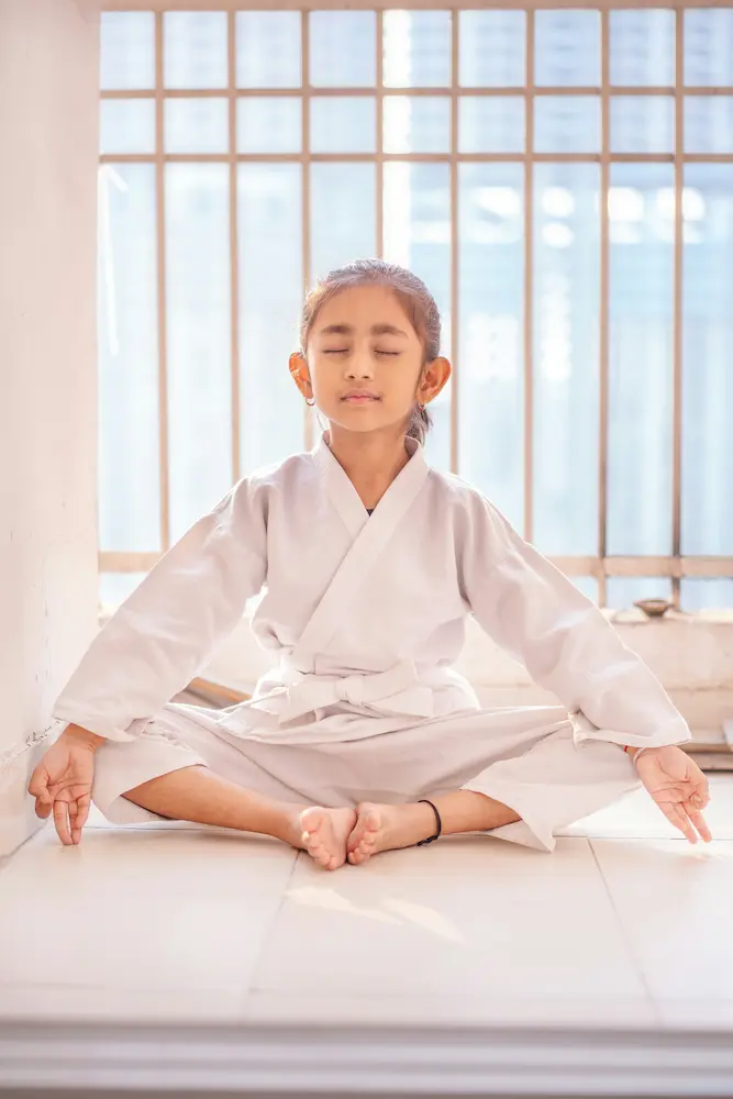 Young martial arts student meditating in dobok embodying Jidokwon philosophy of mental discipline