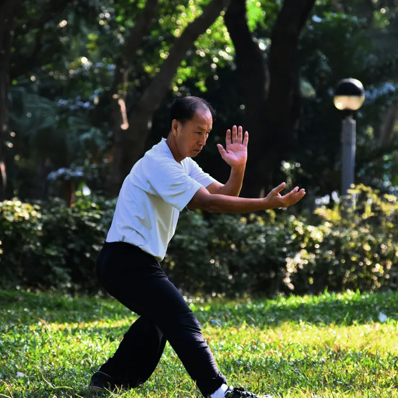 Group of beginners practicing tai chi movements together outdoors