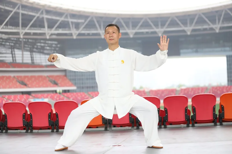 Martial artist holding a low horse stance in a tai chi form, showing the deeper stances that separate Chen style tai chi from Yang style