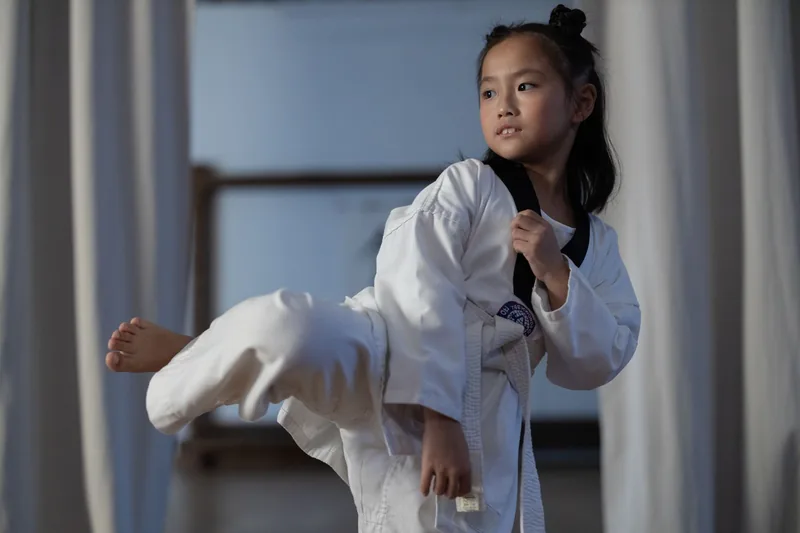 Young TaeKwonDo student holding a balanced kicking stance on the path to junior black belt