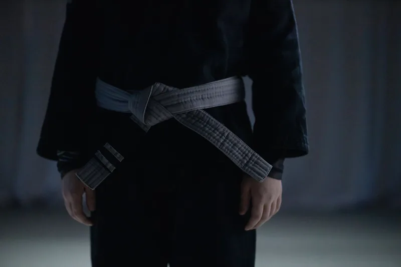 A white belt tied over a gi, the starting rank every jiu jitsu beginner guide is written for
