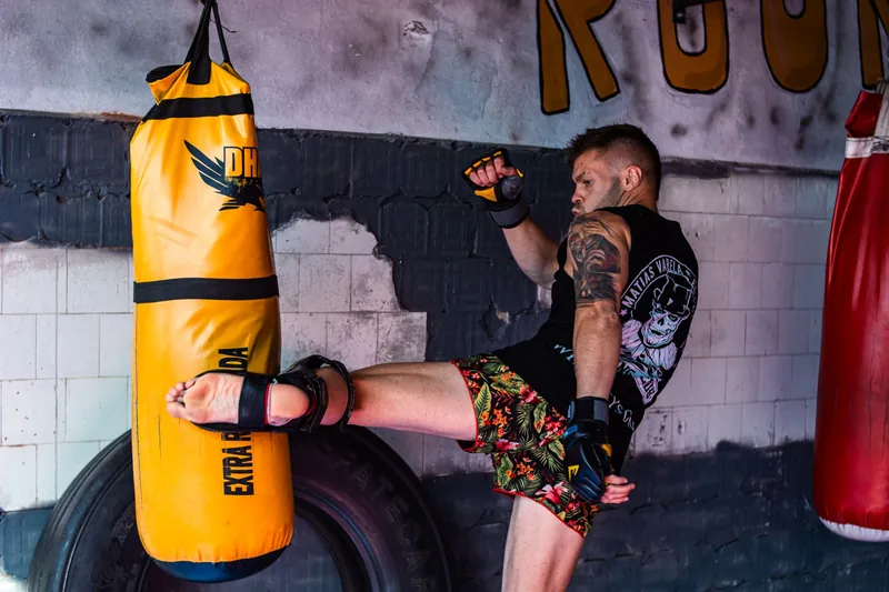 Fighter kicking a heavy bag during MMA conditioning work that drives weight loss