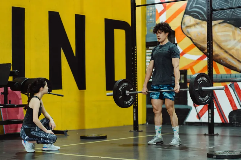 Athlete lifting a barbell during strength work that protects muscle in an MMA body transformation