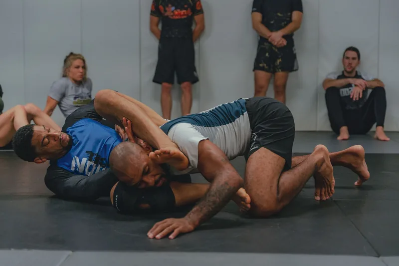 Two athletes drilling takedowns and grappling in a beginner MMA training session
